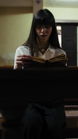 devoted young woman reading prayers in the church on the sacred book