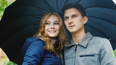 Der-Gut-Gekleidete-Mann-Mit-Seiner-Frau,-Die-Unter-Einem-Regenschirm-Steht-Und-Lächelt-Und-Lacht