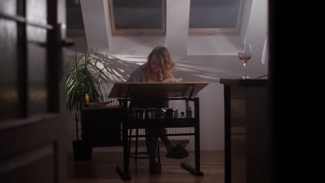 woman painting in a home studio at night