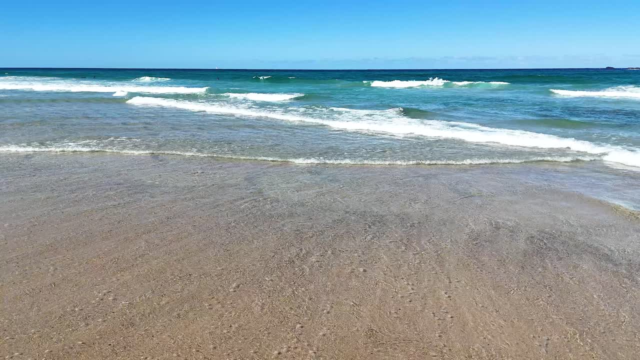 바다의 파도가 모래 해변에 굴러오고