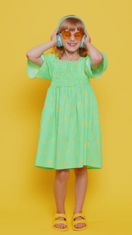 child kid girl in sunglasses listening music on headphones dancing disco fooling around having fun