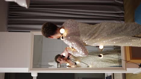 a man in a dress posing in front the mirror with garland on neck, sensually moves