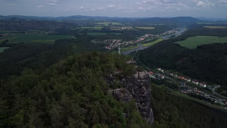 Spektakuläre-Luftaufnahmen-Von-Drohnen,-Die-Auf-Die-Höhe-Eines-Berggipfels-Fliegen-Und-Dort-Absteigen,-Mit-Blick-Auf-Das-Wunderschöne-Tal-Im-Hintergrund-In-Sachsen,-Deutschland