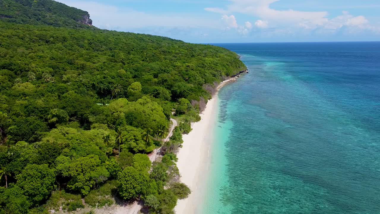 Scenic static aerial landscape view of tropical island of Timor-Leste with pristine white sandy beach, green forest trees, and turquoise crystal clear ocean water