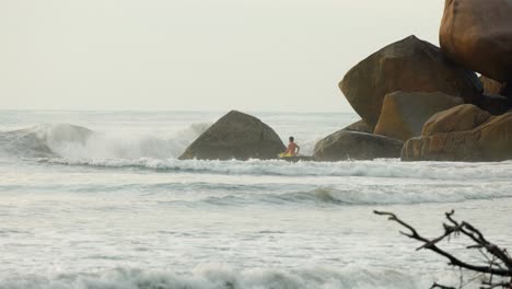 Joven-Entrando-Al-Agua-Con-Su-Tabla-De-Surf-En-Cámara-Lenta