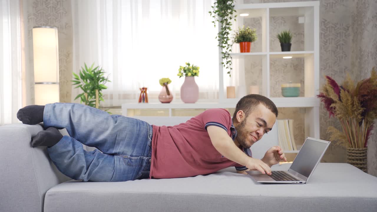 A man with dwarfism works from home on a laptop.