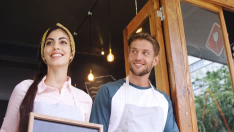 Male-waiter-and-female-waitress-standing-with-open-sign-board-4k