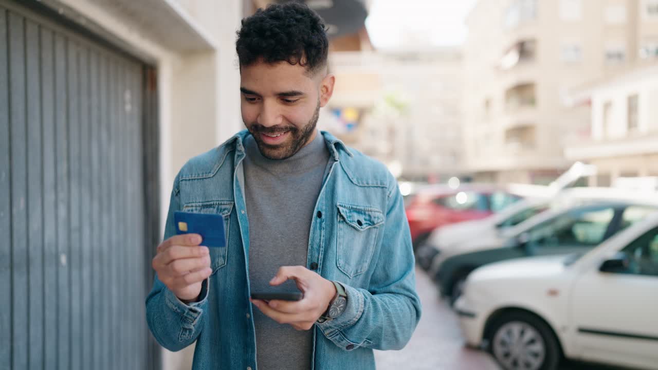 joven árabe usando teléfono inteligente y tarjeta de crédito en la calle