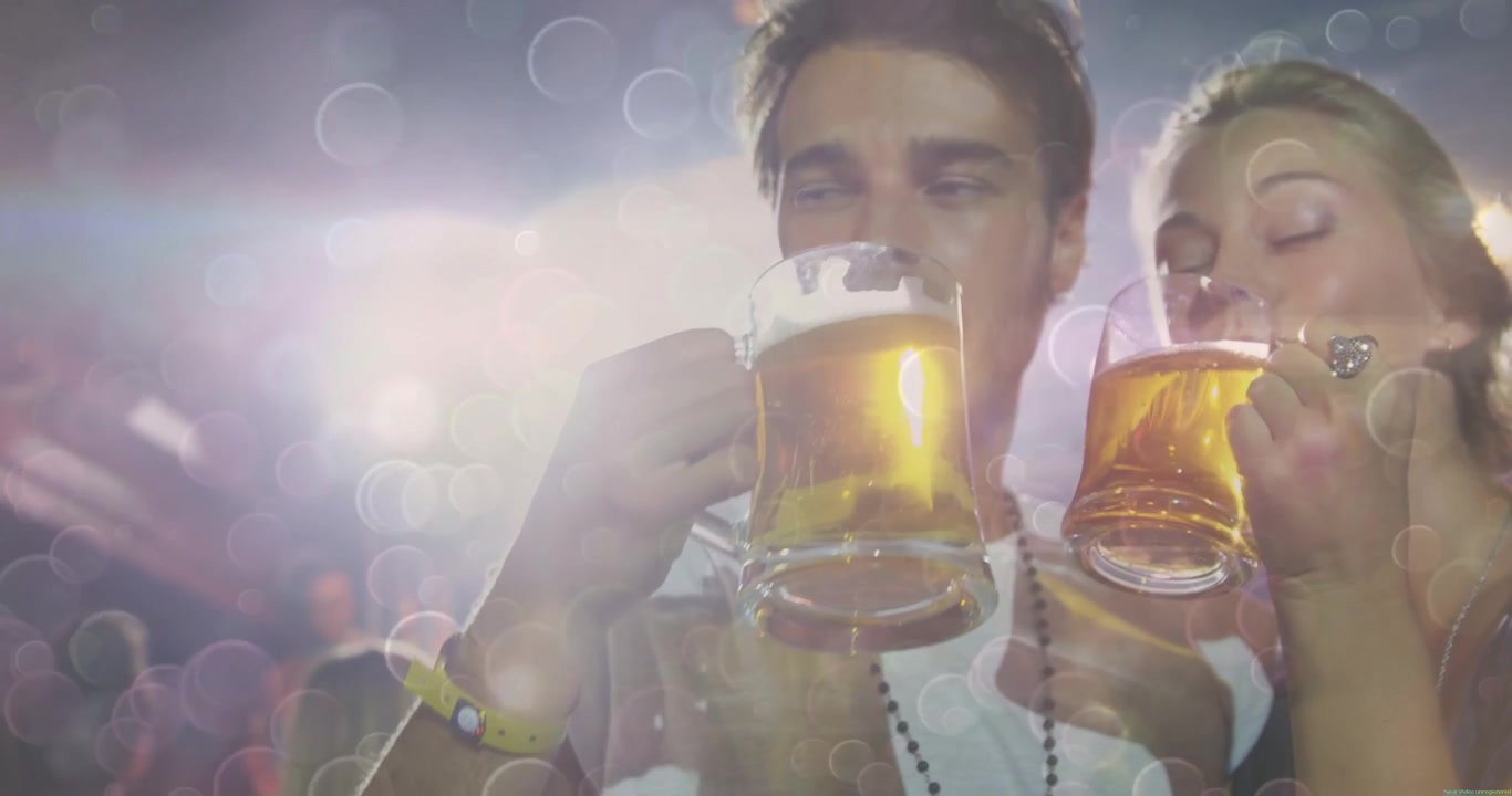 Couple levant des chopes de bière sous les projecteurs dans une salle de concert et partageant des gorgées pour célébrer un spectacle en direct