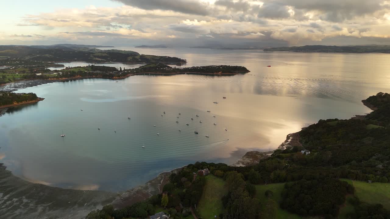 Blackpool Beach and bay, moored boats and cloud reflections on calm water, Waiheke Island, New Zealand, seascape. Aerial drone