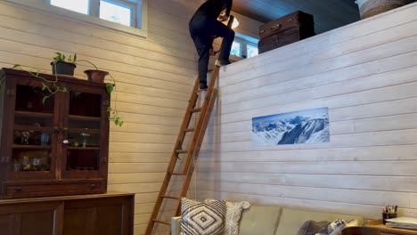 young white male climbing down wooden ladder in ski cabin with white wooden shiplap walls