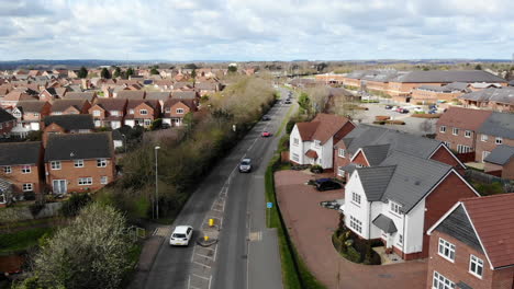 Aerial---A-red-car-driving-on-a-small-residential-main-road's-area