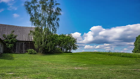 person riding mower driving on green grass at the yard of a rural village. timelapse