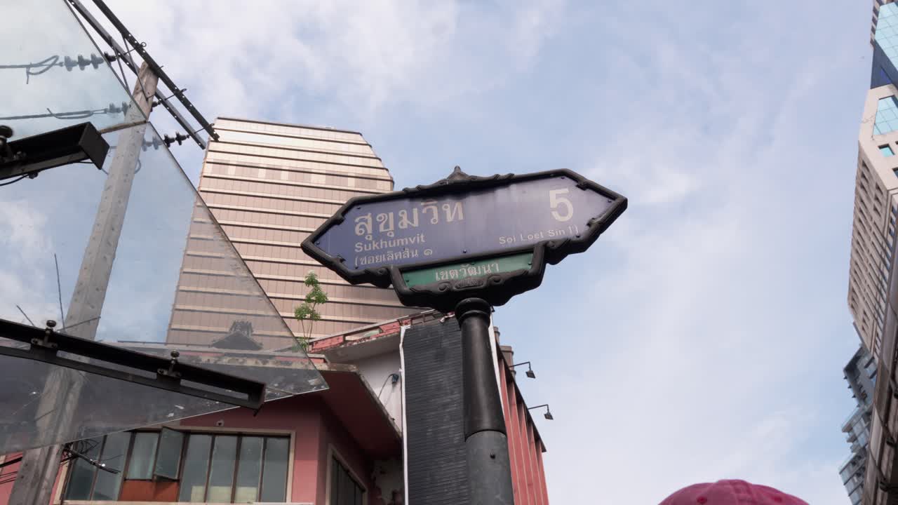 Sukhumvit street name sign, dolly shot under clear blue sky, Bangkok