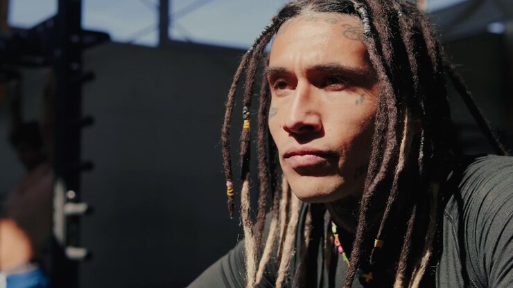 Ung mand med dreadlocks, der hviler efter træning i fitnesscenter