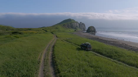 black car driving on dusty road by the beach