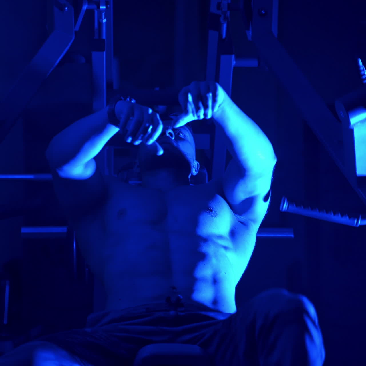 Strong athletic Young Man Doing Dumbbell Incline Bench Press Workout In Gym. Video from below. Focus on a Strong male body. Blue light filter.
