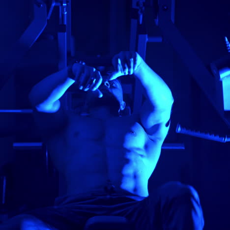 Strong athletic Young Man Doing Dumbbell Incline Bench Press Workout In Gym. Video from below. Focus on a Strong male body. Blue light filter.