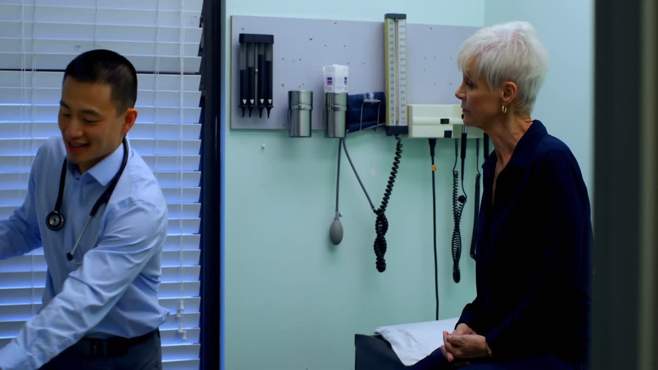 un joven médico asiático y un paciente anciano discutiendo sobre un inhalador de asma en la clínica 4k