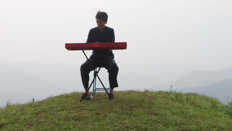 asian handsome man playing the keyboard at the top of a hill