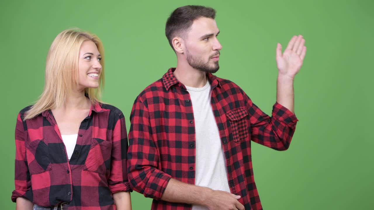 Young couple showing something and talking to camera together