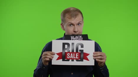 man shopper holding black friday deals advertisement in his month and showing big sale inscription