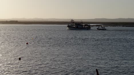 fishing boats leaving and entering the harbor at sunset