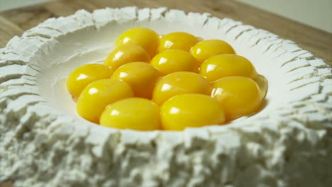 cu pasta making: perfect egg yolks are poured inside a well of flour