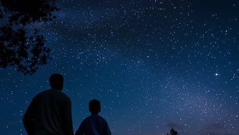 father and son standing together, admiring the breathtaking view of the milky way galaxy on a clear, starry night, creating a magical moment of connection and wonder