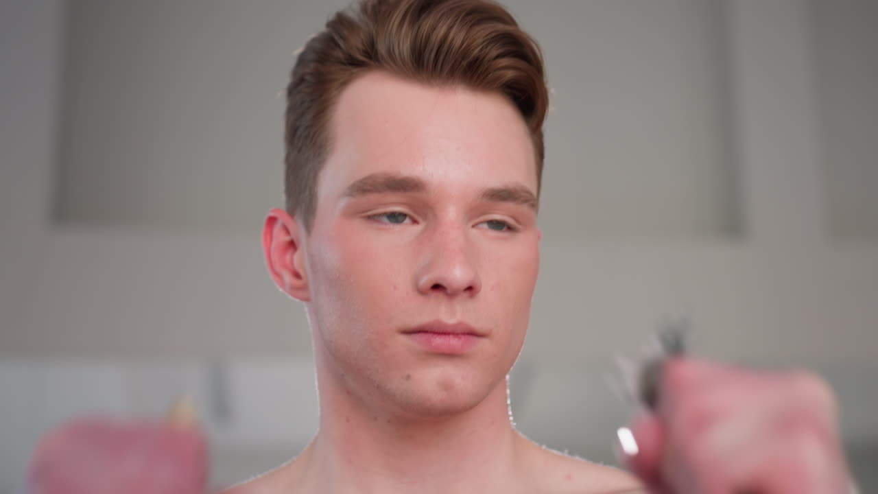 portrait of shirtless young man gripping resistance rope during indoor workout, looking thoughtful and determined while exercising in bright room