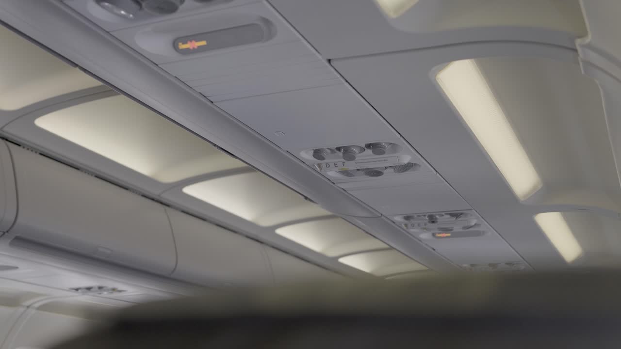 Lights, overhead airplane cabin view with ceiling panels and control buttons visible