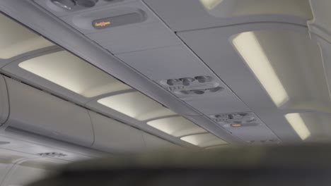 lights, overhead airplane cabin view with ceiling panels and control buttons visible