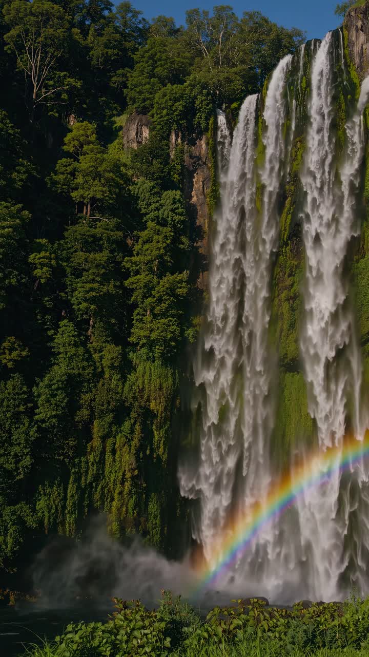 A stunning video still of a majestic waterfall captured from a low angle, with lush greenery