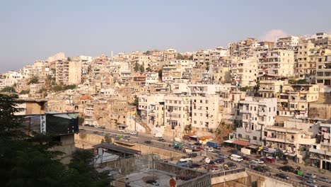 roads driving along road beneath towering middle eastern homes on the hillside above tripoli, northern lebanon