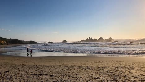 Madre-E-Hijo-Corriendo-De-La-Silueta-De-Las-Olas-Al-Atardecer