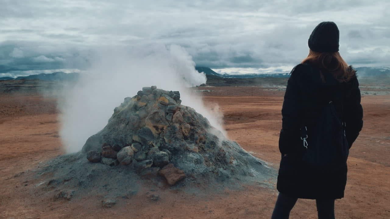 Traveler watching steam rising from a fumarole in a geothermal area in Iceland