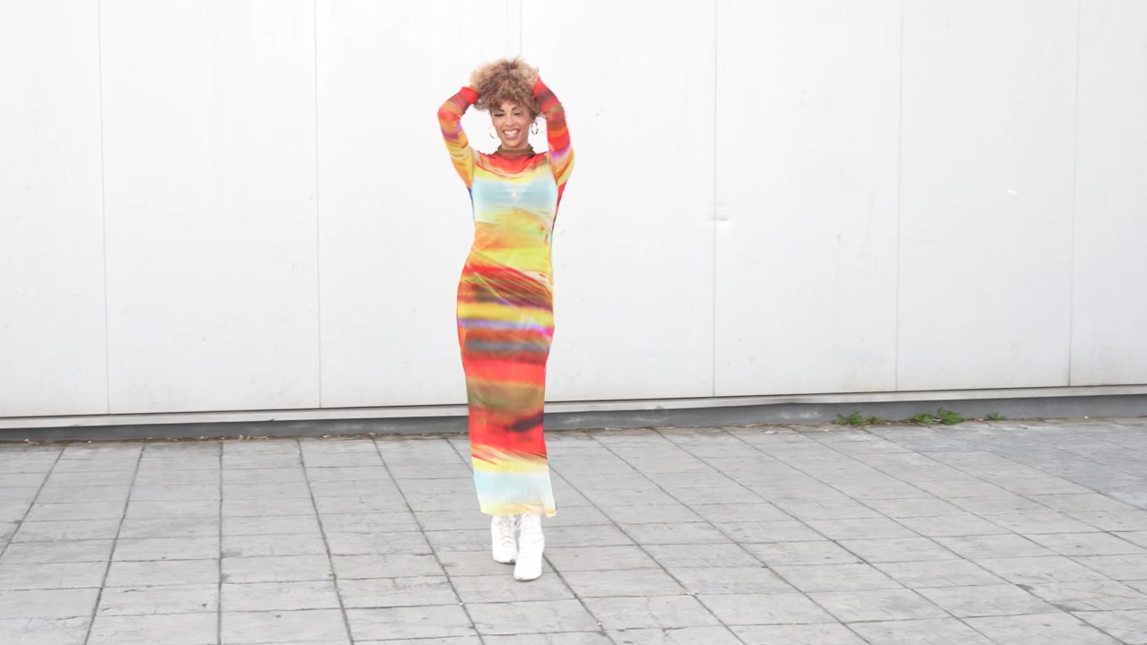 Un abito colorato vivace e all'avanguardia nella moda indossato da una modella e presentato su uno sfondo neutro.