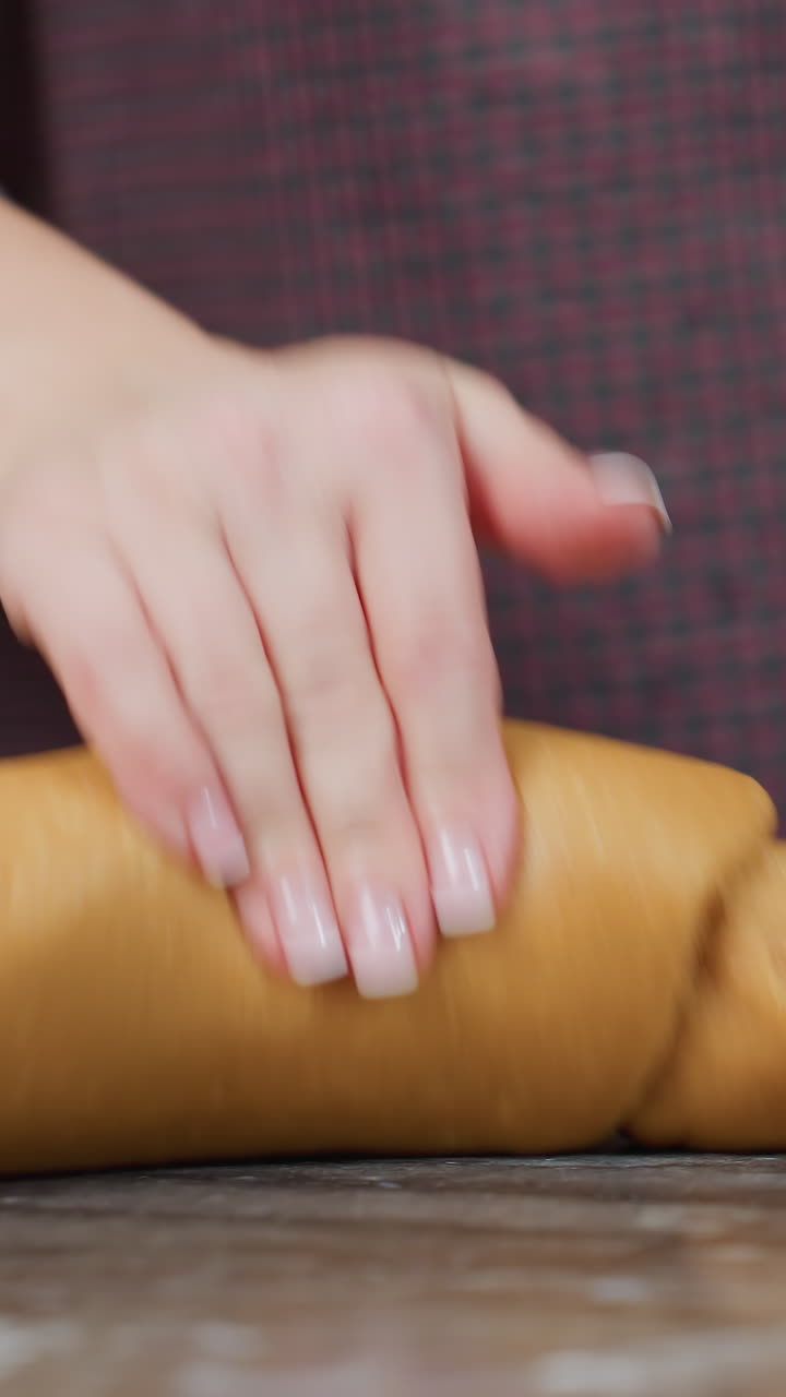 왼손에 팔를 고 부 카운터에 앉아 있는 여성의 부분적인 모습, 오른손으로 신선한 반죽을 고, 편안한 분위기의 현대 부에서 집에서 만든 김 상품을 준비하고 있습니다.