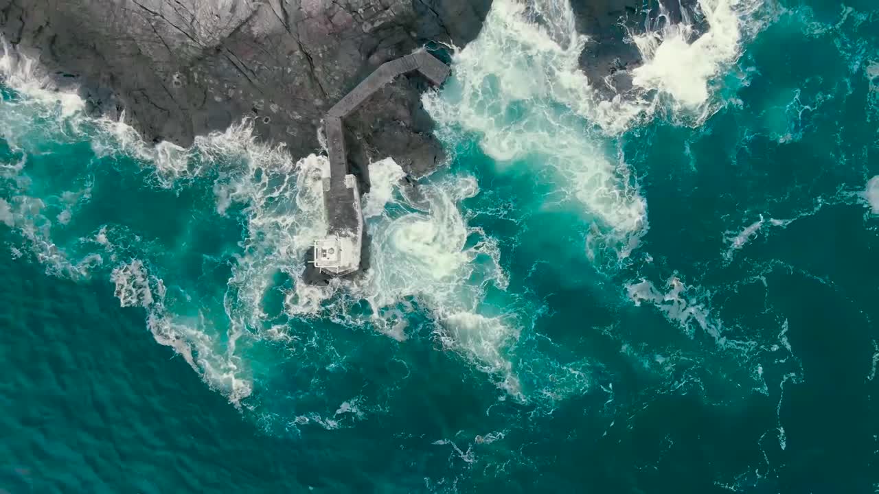 video aéreo de drones de agua de mar azul y verde del océano golpeando la costa donde están presentes acantilados y rocas escarpadas