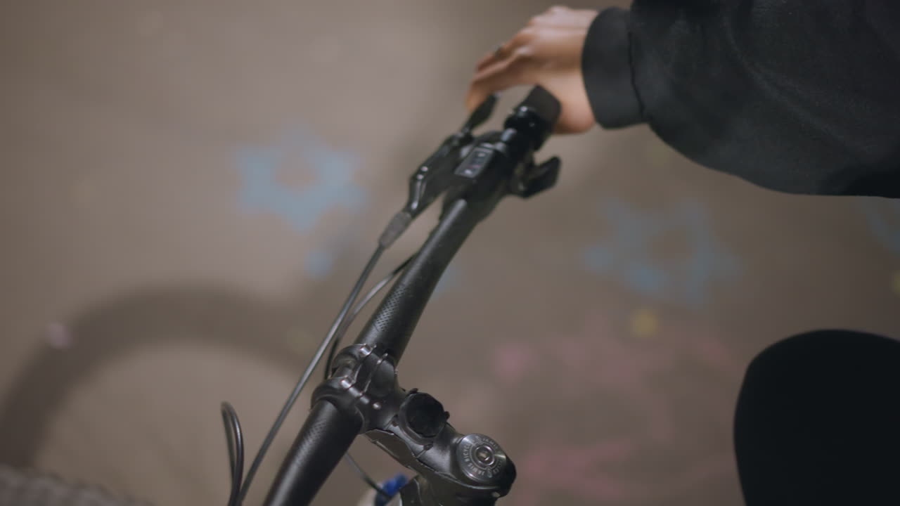 Closeup Bicycle Handlebar Turning Motion, Rider Steering Through Dimly Lit Path, Dynamic Angle Showing Front Wheel Alignment And Subtle Lean, Concentrated Movement And Evening Atmosphere