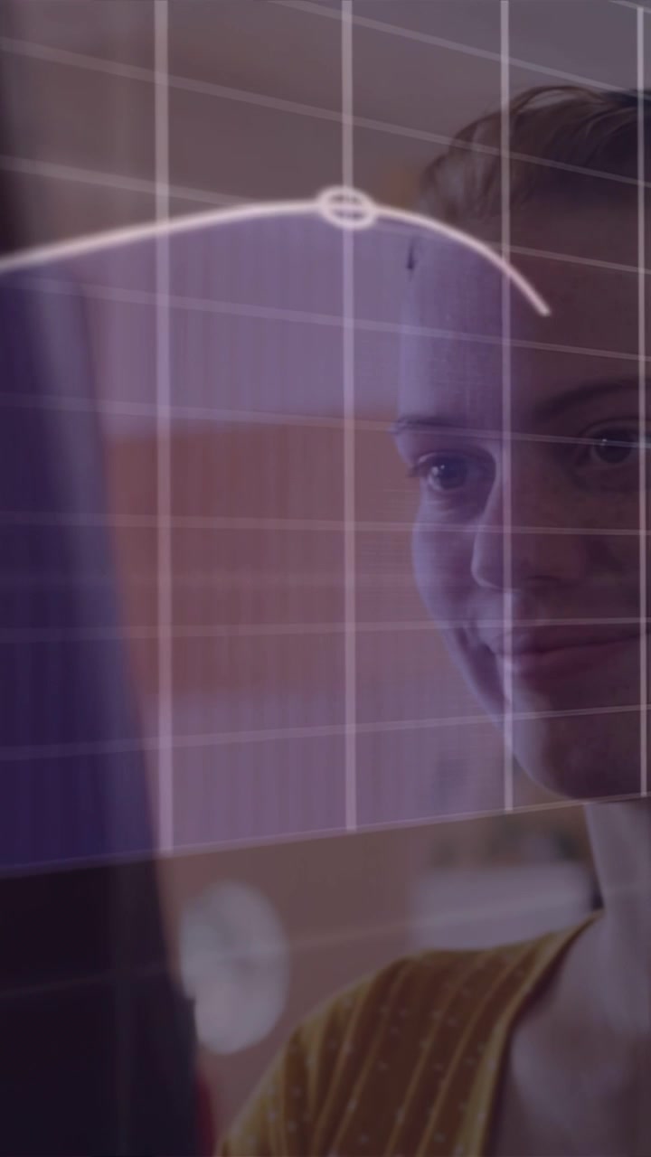 Vídeo vertical: Mulher observando monitor, tela ativando grade e curva de dados em movimento para análises.