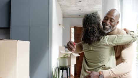 happy biracial couple embracing with cartons at new house, slow motion