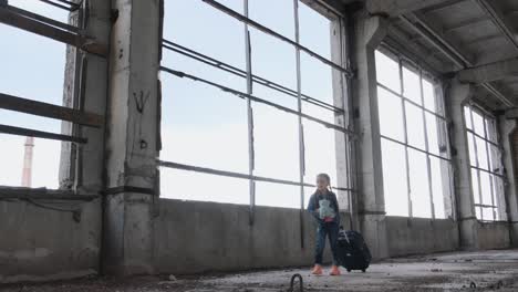 a girl with a suitcase and toy in an abandoned building