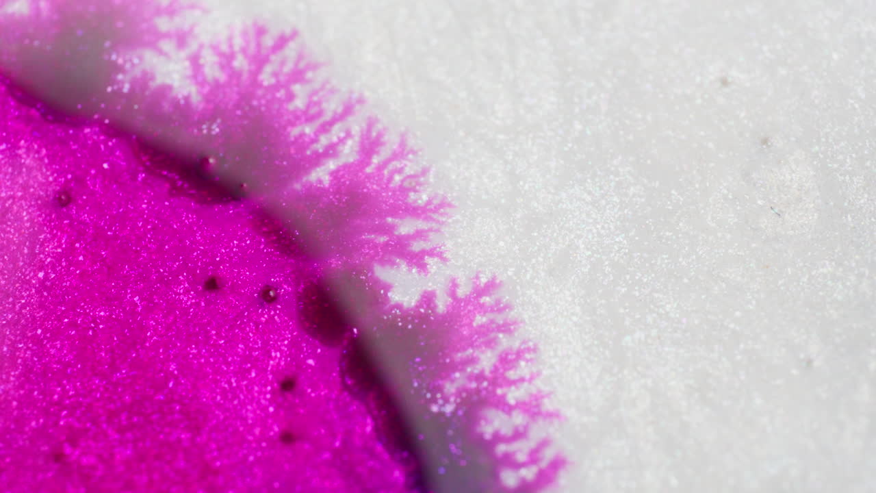 Dark pink ink in motion moving in a white background. Macro close up