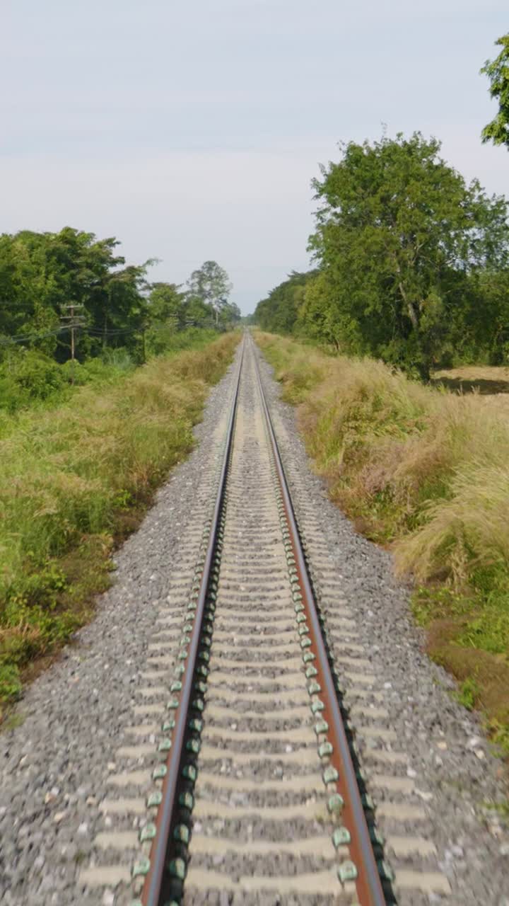 Vertical, POV shot from train going forward of Thailand's Eastern Line from Bangkok to Ban Klong Luk during the day in Thailand