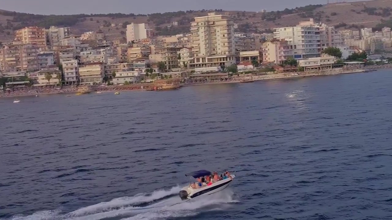 Vista di una barca che naviga sul mare vicino a una città in Albania