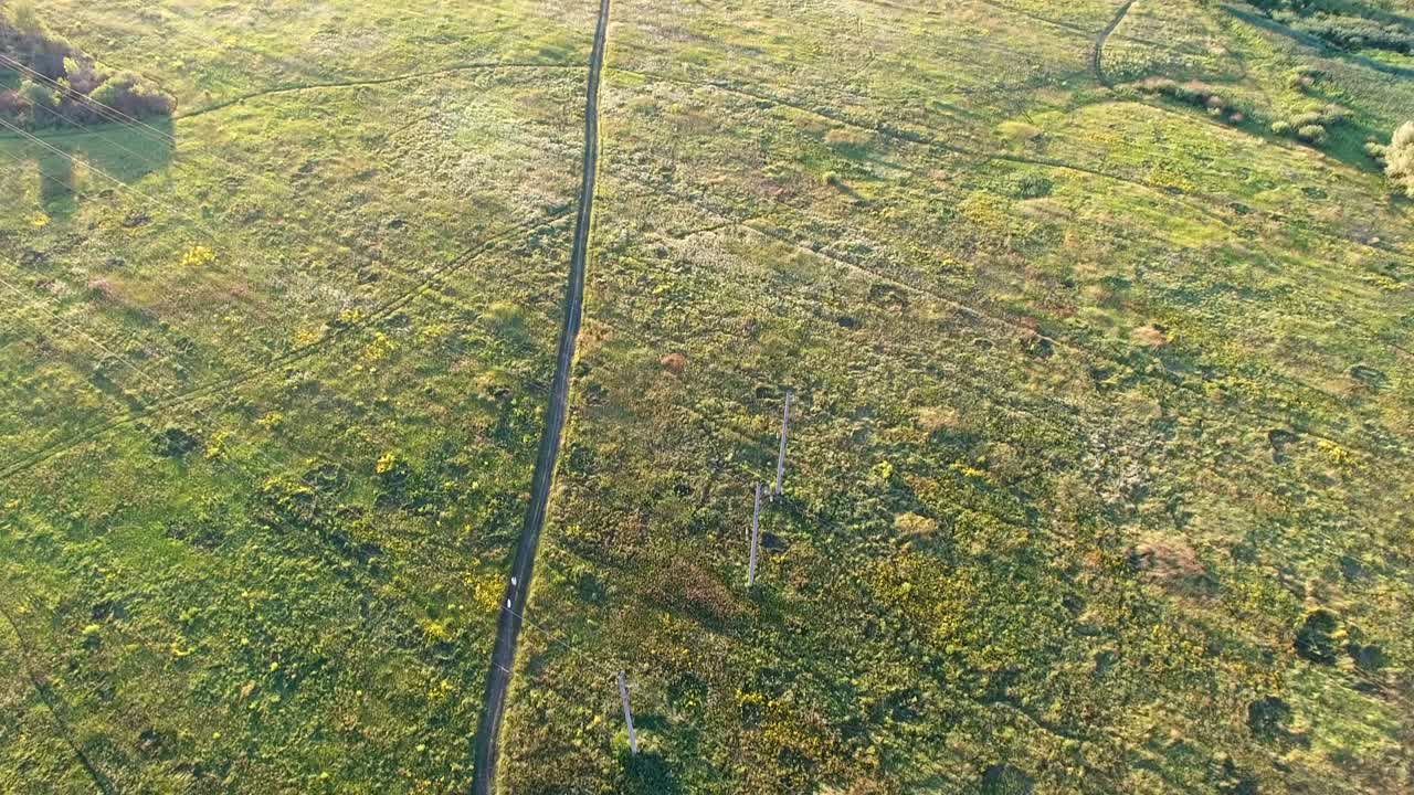 vista aérea de la puesta de sol en los suburbios. hombre con perro caminando por un sendero en un campo, filmado en 4k uhd
