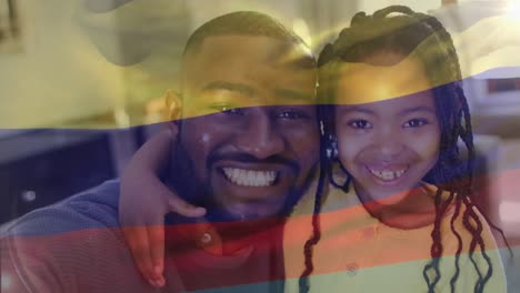 animation of flag of colombia over african american father with daughter