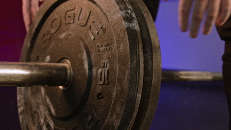 hands adding weight to barbell rod at gym