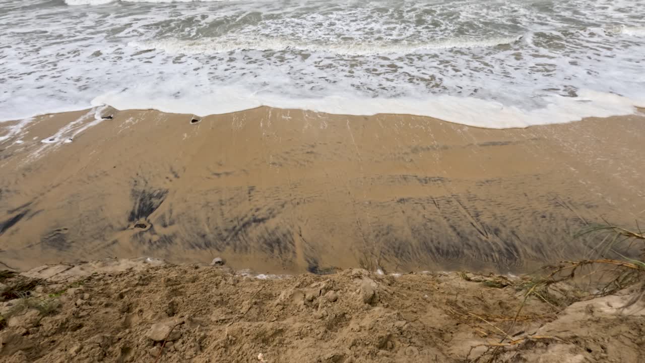 물결이 모래 연안에 부히면서 사이클론 알프레드 (alfred) 기간 동안 해안 침식이 일어나는 것을 보여주는 역동적인 장면은 자연의 원시적인 힘을 포착합니다.
